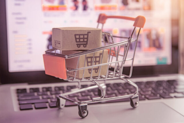 Shopping online concept - Parcel or Paper cartons with a shopping cart logo in a trolley on a laptop keyboard. Shopping service on The online web. offers home delivery