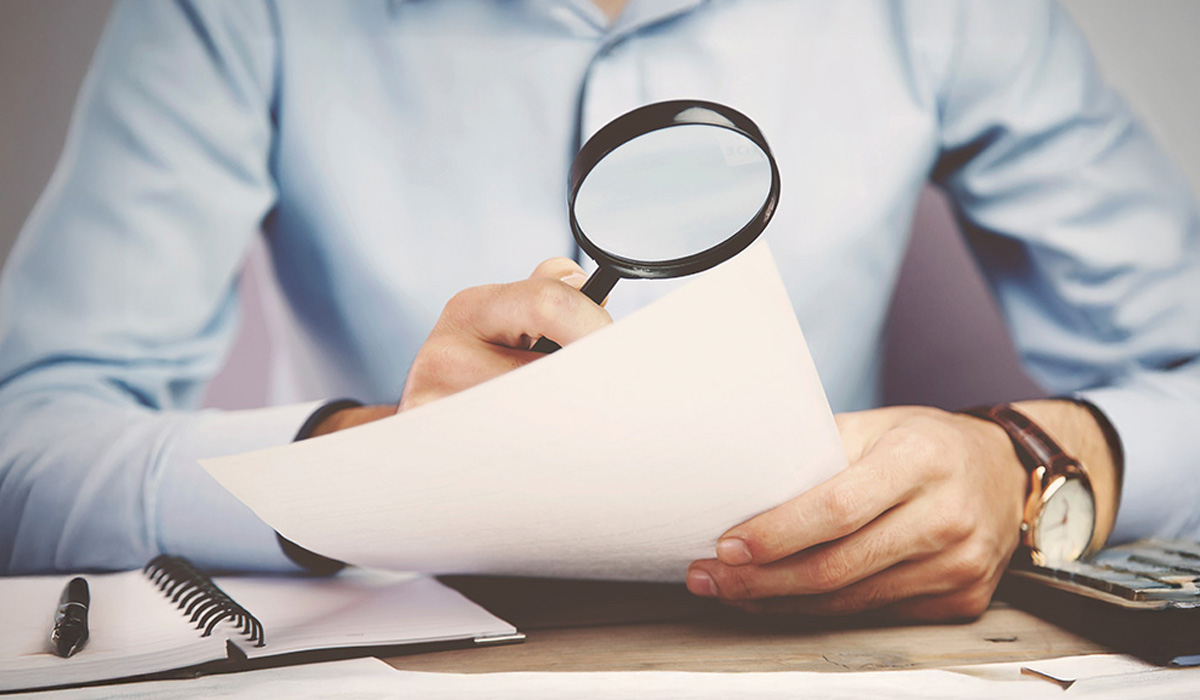businessman looking at document with magnifying glass