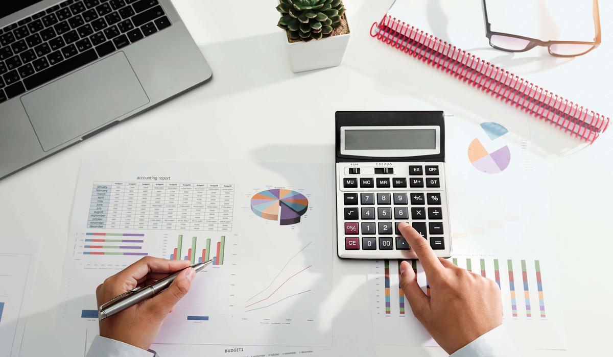 businesswoman working on desk using calculator and laptop analyzing finance accounting in office 
