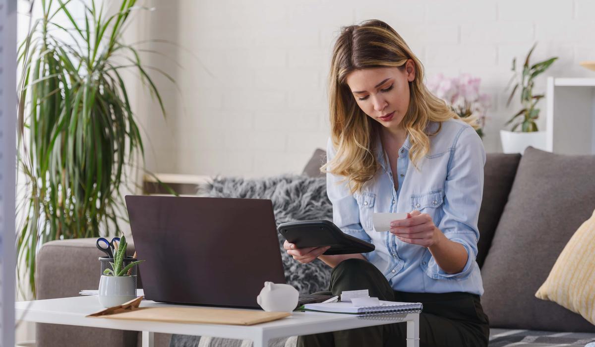 young beautiful woman working on a computer at home calculating monthly expenses doing home budgeting